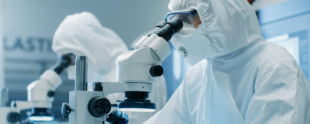 Air sampler certification — suited technicians using microscopes in cleanroom