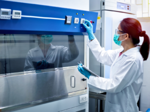Calibration services technician adjusting controls on a laboratory fume hood