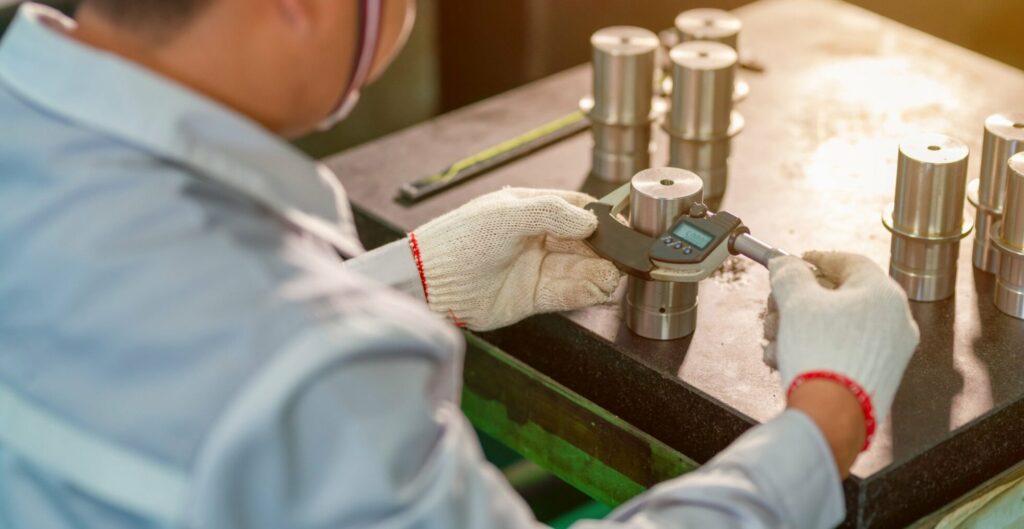 Dimensional calibration services technician measuring metal parts