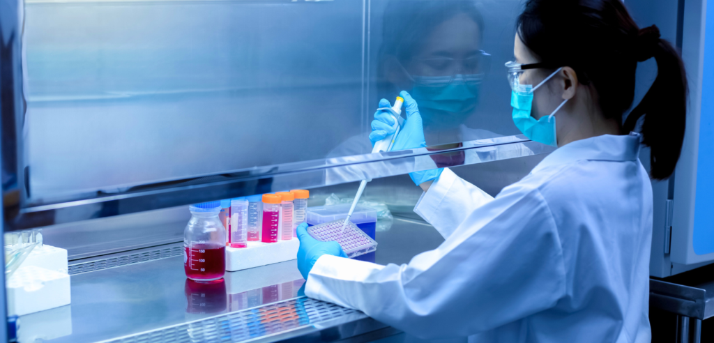 Fume hood service setting where a masked lab professional pipettes into a plate