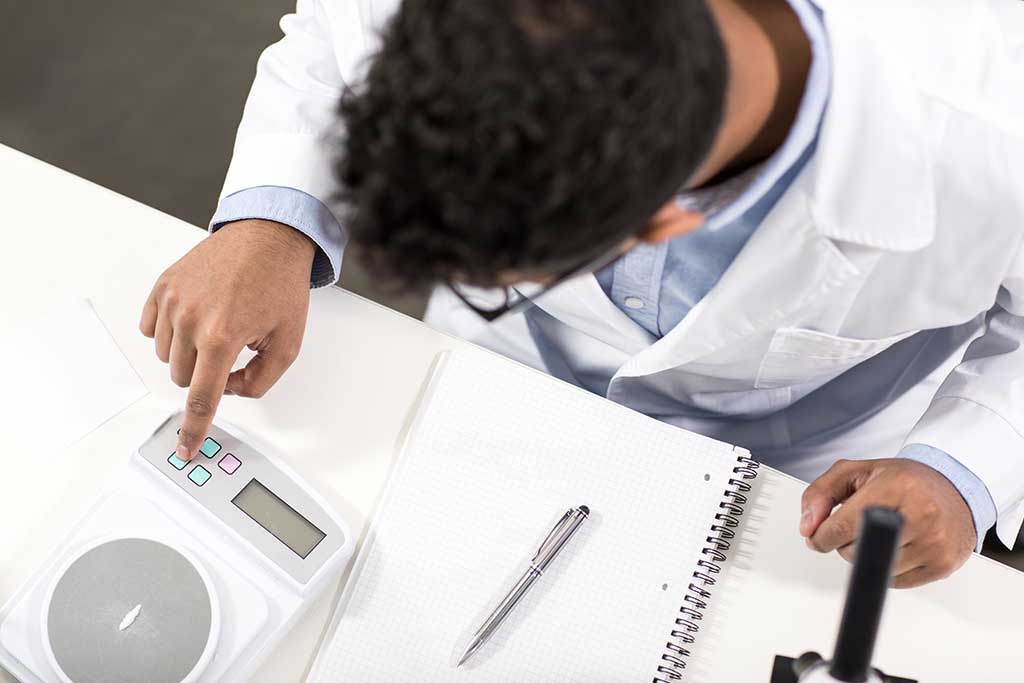 Mass calibration services technician operating a precision balance in a laboratory setting